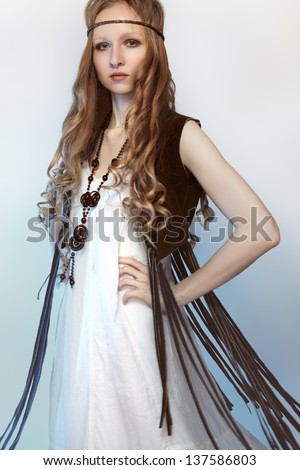 Bohemian woman in spring/summer clothes with beautiful accessories, natural make-up and shiny hairstyle. Perfect long white dress, brown suede jacket and long curly hair. Fashion hippie style.