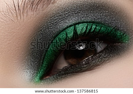 Elegance close-up of female eye with green and black color eyeshadow. Macro shot of beautiful woman\'s face part. Wellness, cosmetics and make-up.