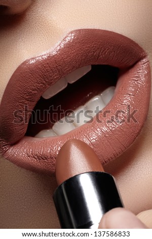 Part of attractive woman\'s face with fashion brown lips makeup. Professional make-up artist applying lipstick. Sexy open female mouth