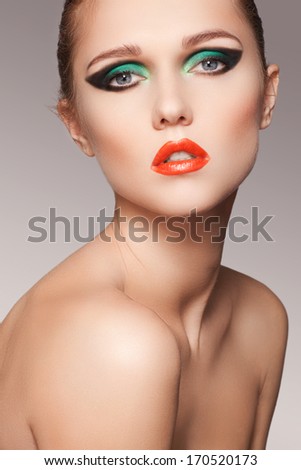 Closeup beauty portrait of attractive model face with bright visage. Chic green eye makeup and red lips make-up