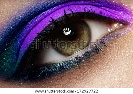 Macro shot of woman\'s beautiful green eye, bright and deep colors make-up. Dark purple eyeshadow on eyelid. Sexy view, sensual look