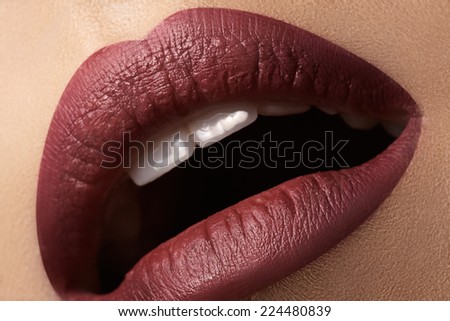 Close-up of woman\'s lips with bright fashion dark red makeup. Macro cherry lips make-up. Evening sexy visage