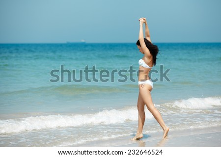 Happy woman in white bikini swimwear open her heart to sun. Vacation, beautiful sea and natural. Tan girl in summer. Perfect body shapes, relaxing soul.
