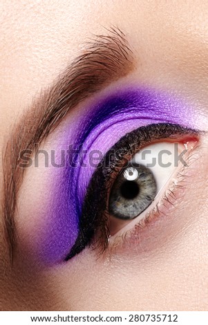 Cosmetics & make-up. Beautiful female eye with sexy black liner and bright purple makeup. Fashion classic arrow shape on woman\'s eyelid. Chic evening make-up