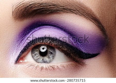 Cosmetics & make-up. Beautiful female eye with sexy black liner and bright purple makeup. Fashion classic arrow shape on woman's eyelid. Chic evening make-up