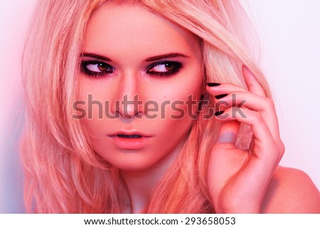 Punk rock style or halloween make-up. Fashion woman model face with bright glamour makeup. Perfect skin, black gloss eyeshadows on eyes and dark brown glossy lips visage. Portrait in red light