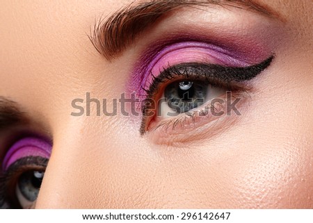 Beautiful female face with sexy black liner and bright purple makeup.