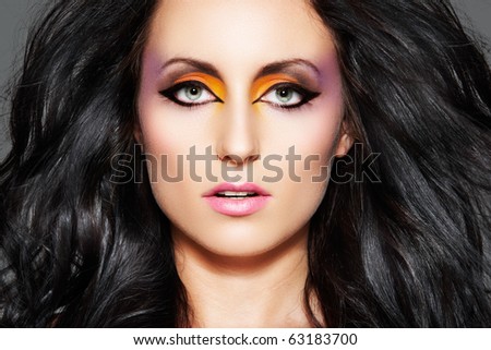 Portrait of sensual woman model with oriental bright make-up, long volume black hair. Fashion colorful hairstyle. Beautiful female face.