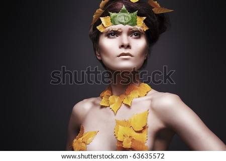 Autumn and autumnal fashion style. Carnival costum with gold leaves. Beauty and fashion, cosmetics and make-up. Portrait of luxury fairy woman model with evening make-up and creative hairstyle.