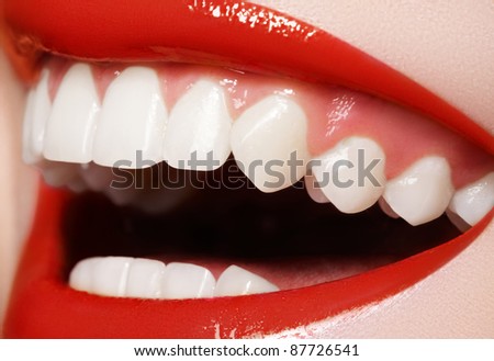 Close-up happy female smile with healthy white teeth, bright red gloss lips make-up. Cosmetology, dentistry and beauty care. Macro of woman\'s smiling mouth