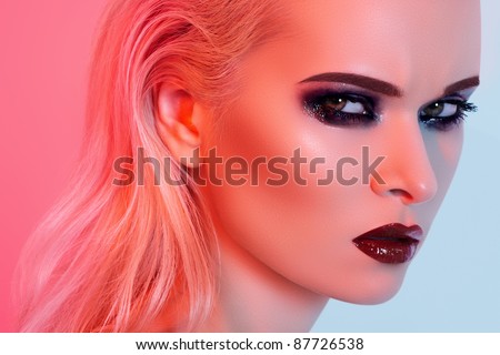 Punk rock style or halloween make-up. Fashion woman model face with bright glamour makeup. Perfect skin, black gloss eyeshadows on eyes and dark brown glossy lips visage. Portrait in red light
