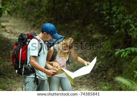 Young couple looking at the map in the forest