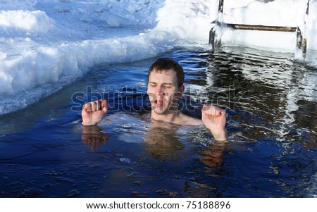 Young man swimming in winter cold water