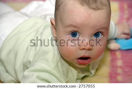 little infant with big blue eyes laying on the stomach