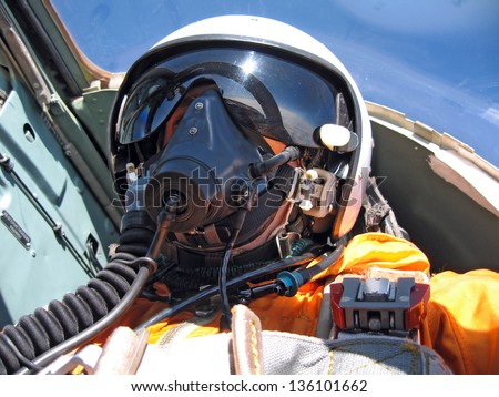 military pilot in the plane in a helmet in dark blue overalls against the blue sky