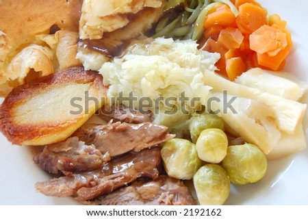 Traditional English sunday roast lamb dinner with yorkshire pudding, fresh garden vegetables and gravy, macro