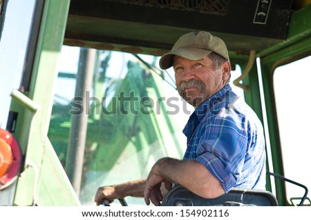 A Candid Portrait Of A Senior Male Farmer Sitting In A Tractor.