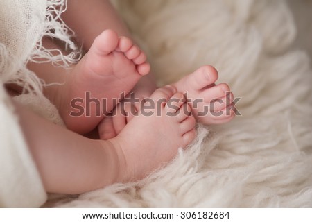 A closeup shot of the feet of twin girl babies. Shot in the studio on a sheepskin rug.