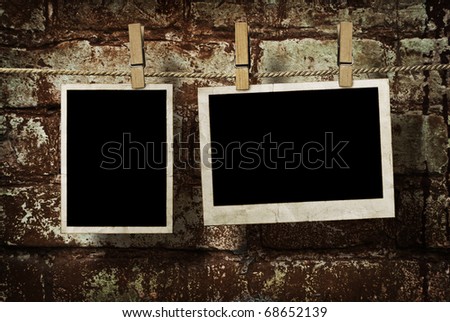 pictures on a rope with clothespins, with clipping path for images, in front of a brick wall