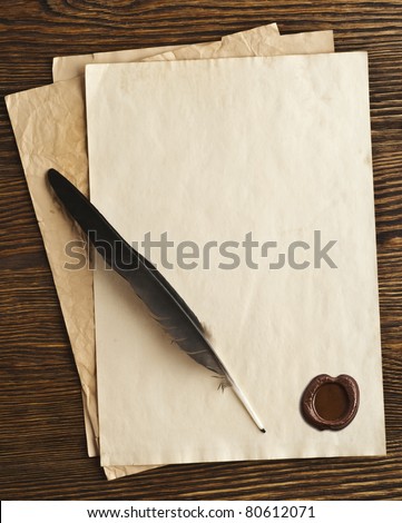 old paper and feather with a wax seal on a wooden background