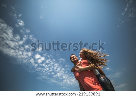 Girl hug her boyfriend from behind on background of sky
