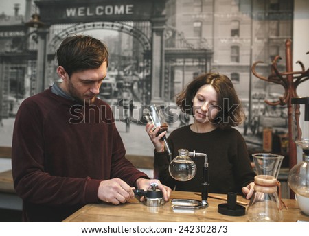 Vintage couple preparing coffee with vacuum coffee maker.Coffee shop.  Vintage toned