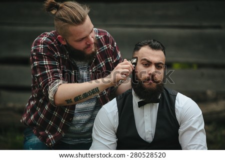 barber shaves a bearded man Outdoors