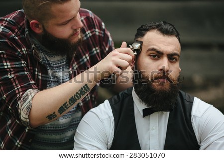 barber shaves a bearded man Outdoors