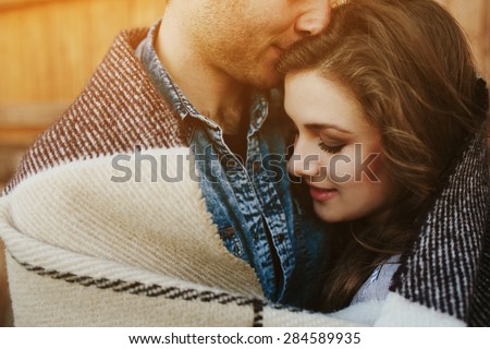 Young couple in love wrapped in plaid standing and looking at each other