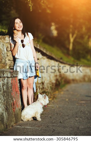 Girl with ice cream and dog against the wall