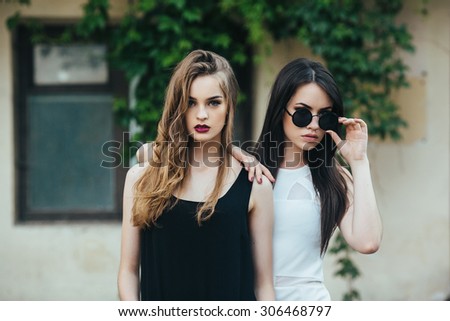 Two beautiful young girls in dresses posing in front of house