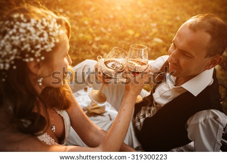 Beautiful wedding couple at a picnic under a tree drinking champagne