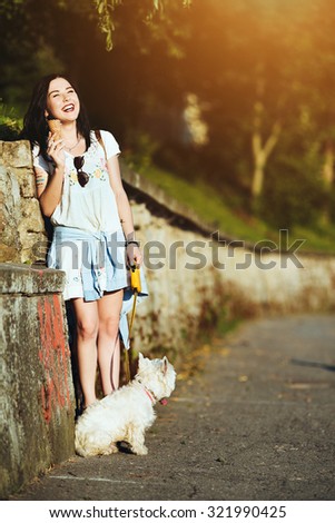 Girl with ice cream and dog against the wall