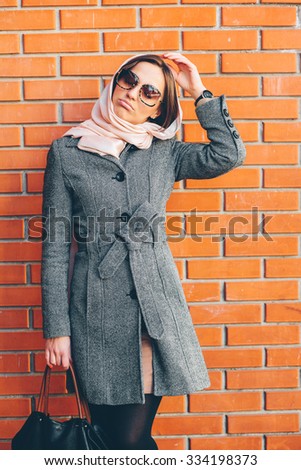young and beautiful girl posing on a background of red brick wall
