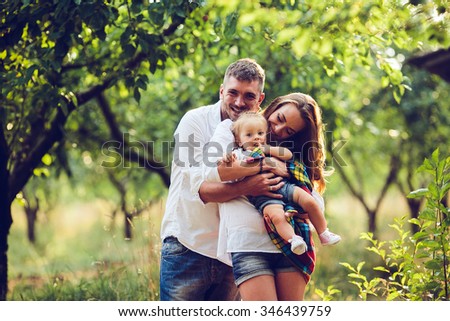 dad, mom and little girl on the farm on a background of trees