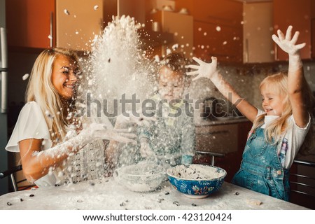 mother and children playing on kitchen with flour