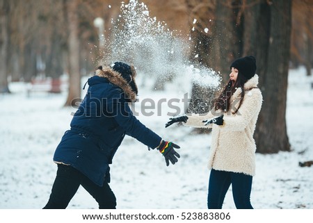 boy and girl playing with snow in snow-covered park
