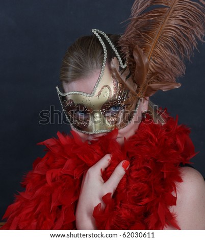 Pretty spectacular woman on a dark background with a mask and feathers, a fan