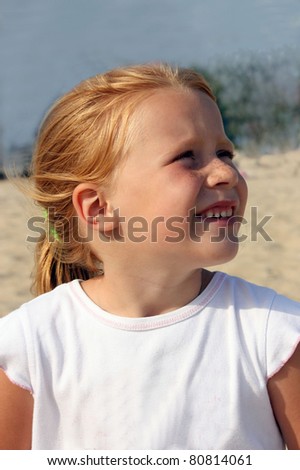 Little Redhead girl with freckles, looks into the blue sky