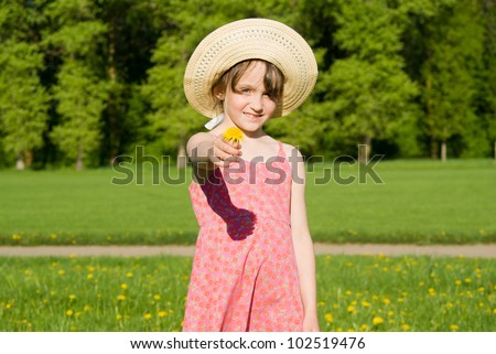 The girl in the hat offers a flower, in nature