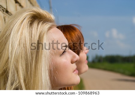 Two girls stand at the wall and look into the distance on the nature