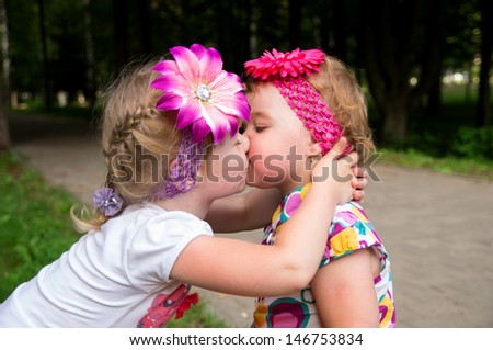 little girl kisses its little sister on the nature