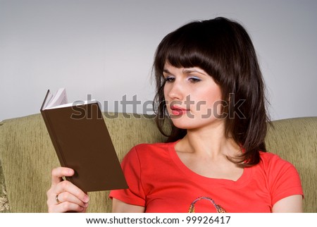 beautiful girl reading a book while sitting on the couch