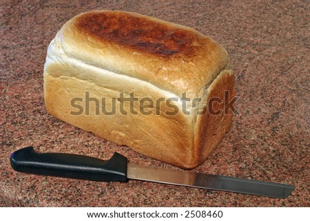 a loaf of freshly baked bread and a knife on a granite worktop