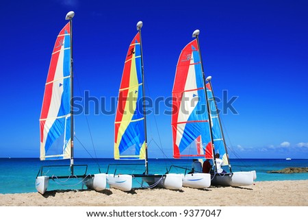 three catamaran's lined up on a beach with the owners in Barbados, just waiting to be hired