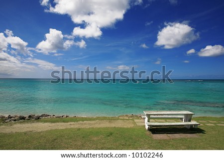 a picnic table situated along a coast road overlooking the Caribbean Sea in Barbados