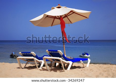 two sun loungers lying underneath a parasol on a deserted beach in Barbados