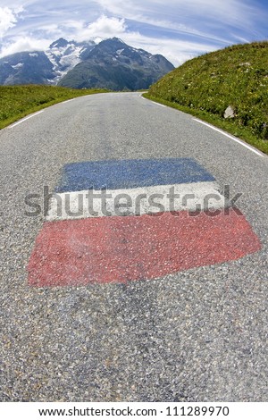 Road in french alps, with painted flag. France.