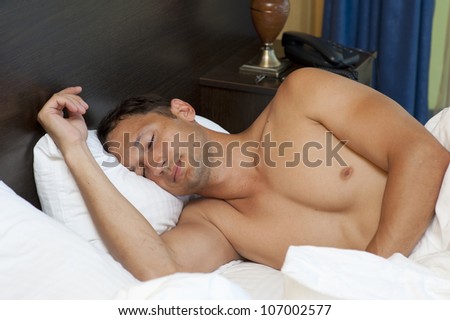 Portrait of a shirtless young man sleeping on the bed at home - Indoor