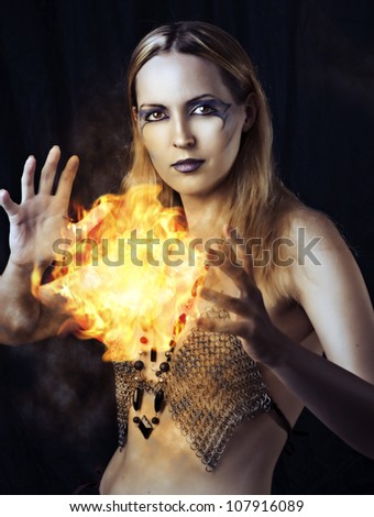 Portrait of dangerous woman witch with fire ball and dark make up
